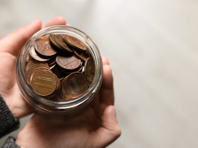 photo of cupped hands holding a jar of pennies